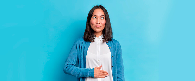 Mulher com a mão na barriga, feliz, sobre como aumentar a saciedade