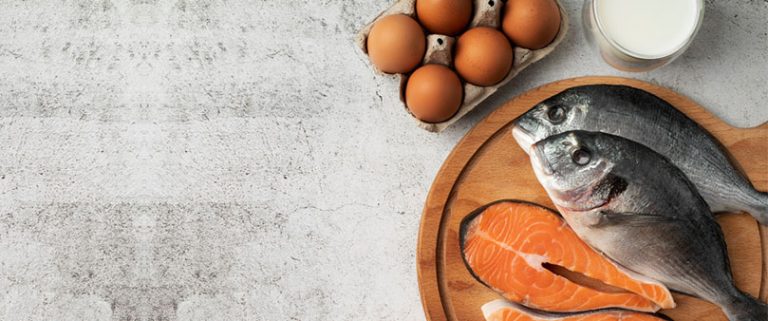 Ovos, peixe e leite sobre uma mesa representando os alimentos ricos em metionina.