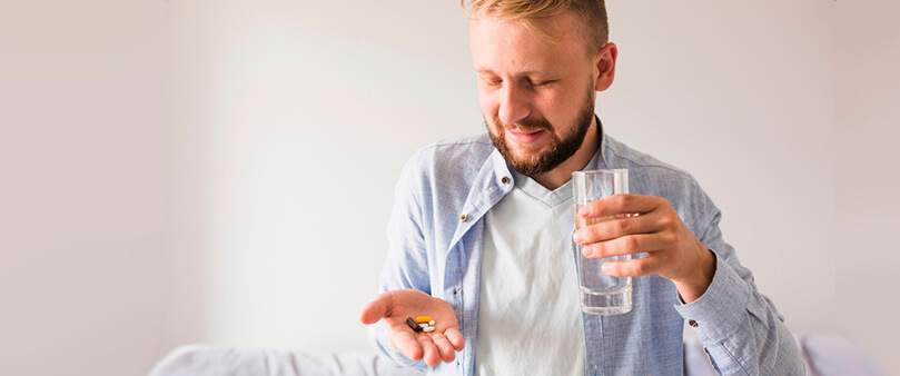 Homem branco segurando comprimidos do medicamento slendesta